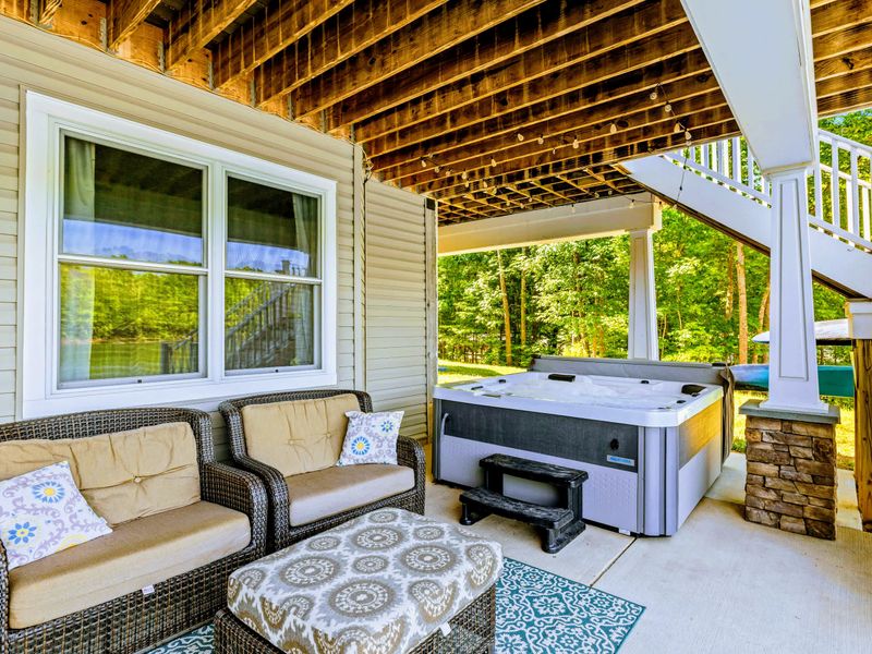 Covered Patio - Cushioned lounge seating under a warm wood ceiling, with the grill close and the lake in full view.