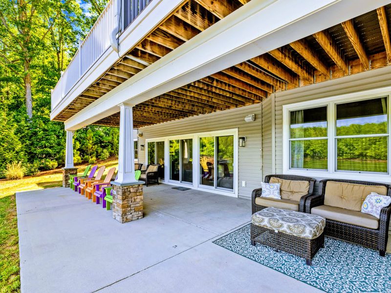 Covered Patio - Lounge seating and a row of colorful Adirondack chairs face the lake from beneath the upper deck.