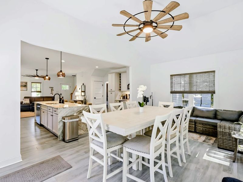 Dining Room - A farmhouse table for the whole group under a statement windmill fan, framed by yard views.