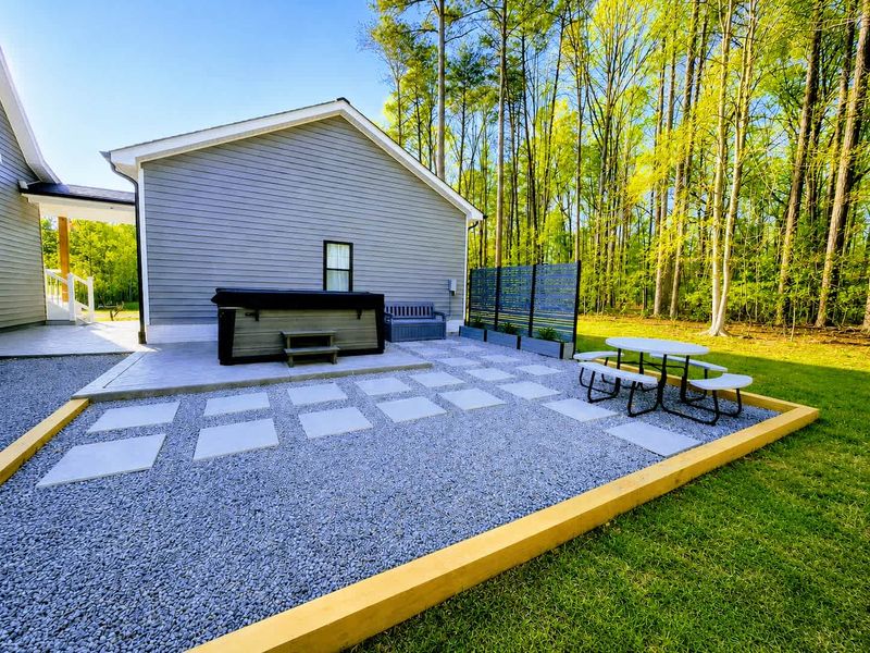 Hot Tub - A spacious hot tub anchors the paver patio, framed by tall pines for shade and privacy.