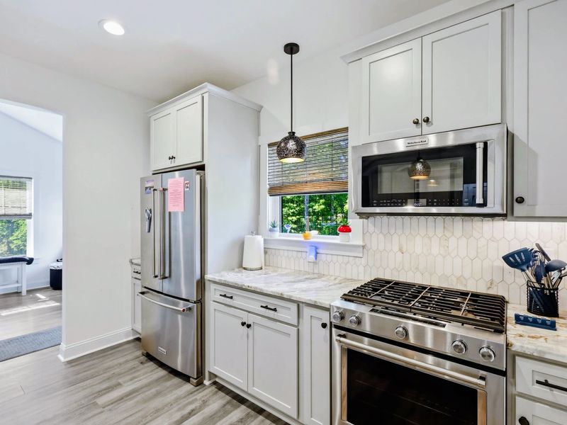 Kitchen - Stainless appliances, pendant lighting, and miles of marble counter for cooking together.