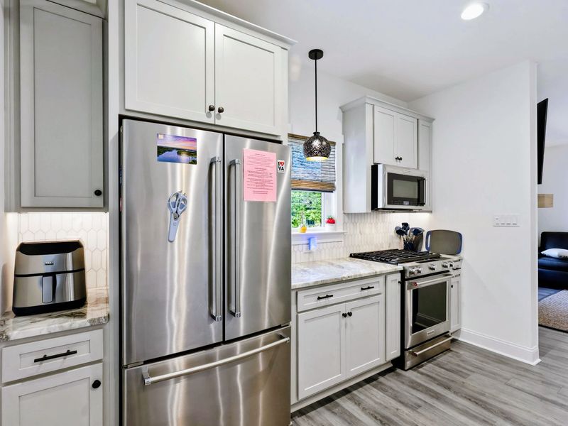 Kitchen - Gas range and custom cabinetry open to the dining and living areas for easy entertaining.