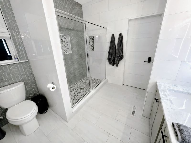 Primary Bath - Glass-enclosed walk-in shower with mosaic tile in a clean, spa-like ensuite.