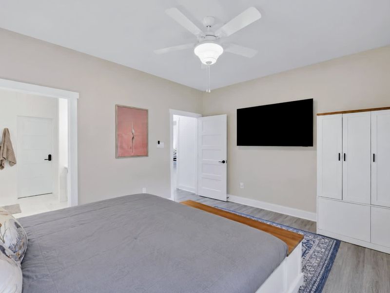 Primary Suite - Wall-mounted TV, generous closet, and a doorway to the private ensuite bath.