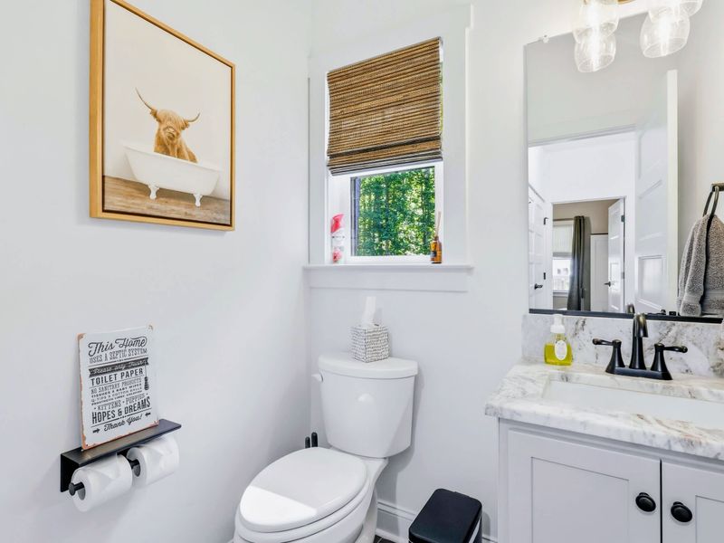 Half Bath - Convenient main-floor powder room with a marble-top vanity and a playful highland-cow print.