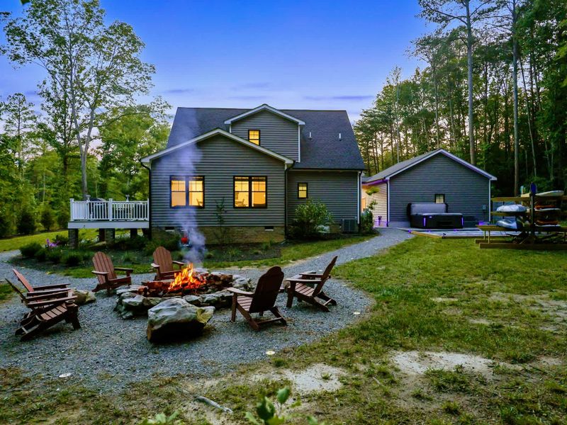 Fire Pit - Flames crackle against the night, the lit home and hot tub glowing just beyond.
