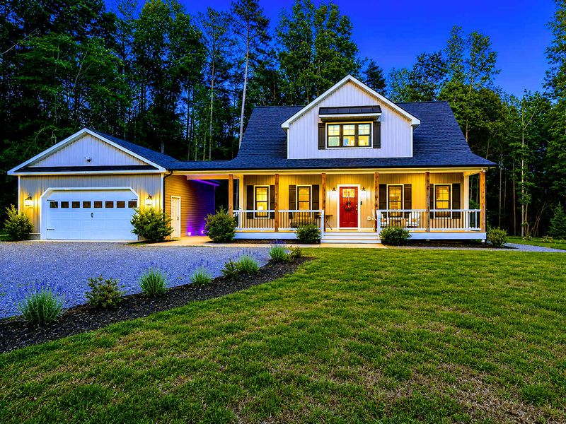 Exterior - The craftsman farmhouse glows at twilight, wraparound porch lit and welcoming after a day on the water.
