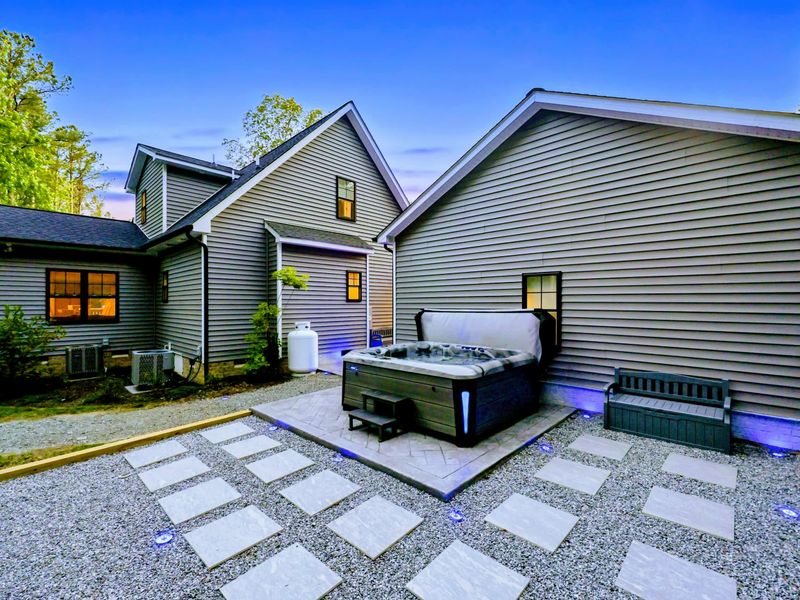 Hot Tub - Settle into the spa as dusk falls, patio lights glowing against the surrounding woods.