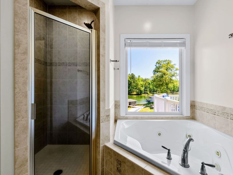 Primary Suite - Soak in the jacuzzi tub with the lake in view, the tiled walk-in shower right beside it.