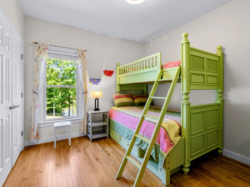 Twin Over Full - Playful lime bunk bed with rainbow striped bedding, a sturdy ladder, and butterfly decor by a sunny window.