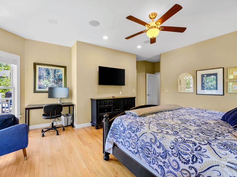 Primary Suite - King bed, with a mounted TV, long dresser, and desk workspace with a monitor nearby.