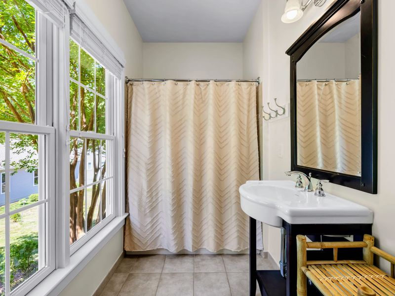 Queen Guest Bdrm - The ensuite bath gets wonderful light from big windows, with a console sink and curtained shower.