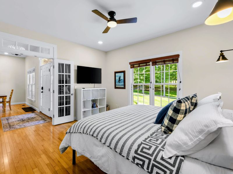 King Guest Bdrm - King bed dressed in crisp stripes, with a wall-mounted TV and French doors off the entry.