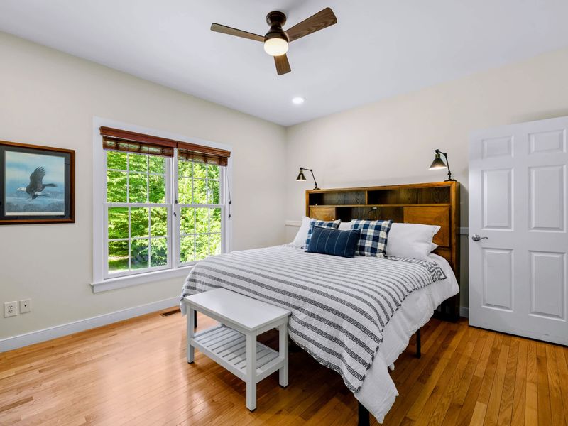 King Guest Bdrm - A bookcase headboard and swing-arm reading lamps make this a cozy spot, with leafy views outside.