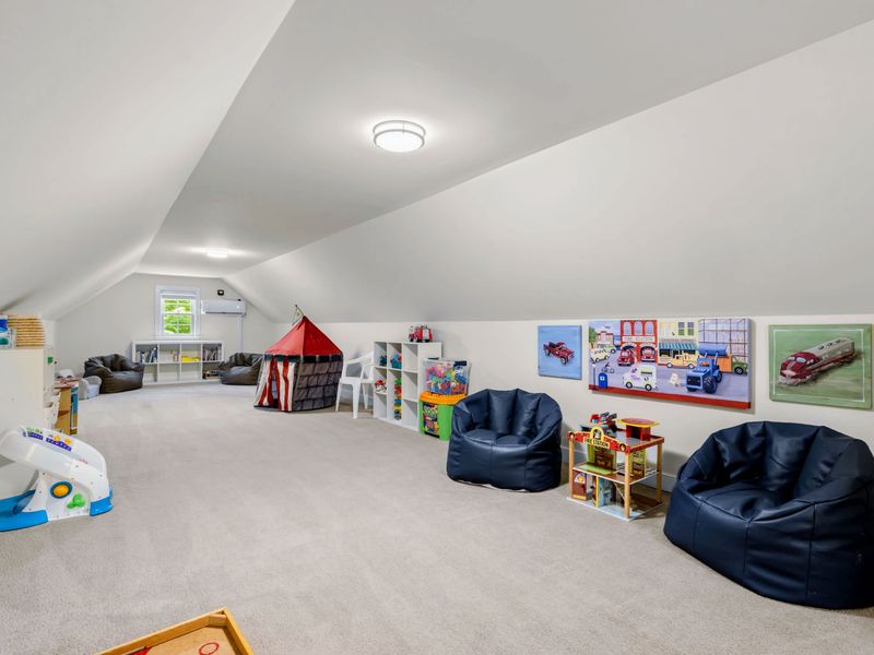 Loft - Bean bag chairs and a play tent fill this carpeted kids' playroom, vintage truck art lining the sloped walls.