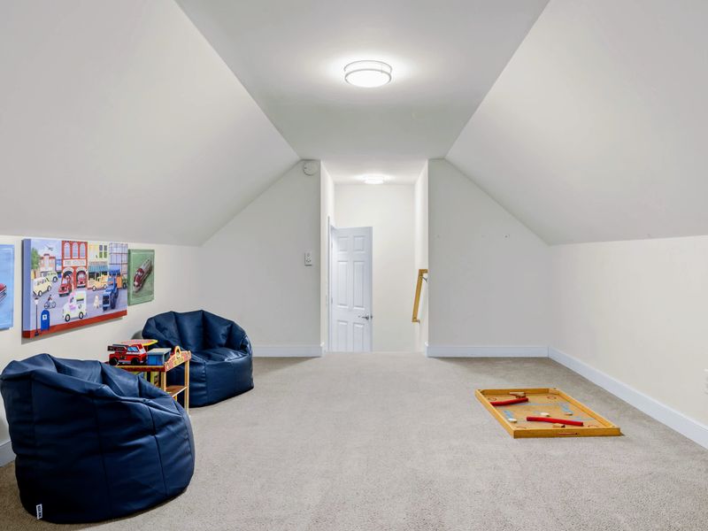 Loft - Large carpeted play space under angled ceilings, with bean bags and a wooden Nok Hockey game ready to go.