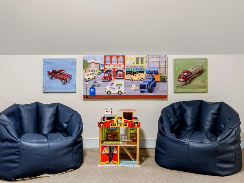 Loft - Two navy bean bag chairs flank a toy fire station beneath playful vintage truck artwork.