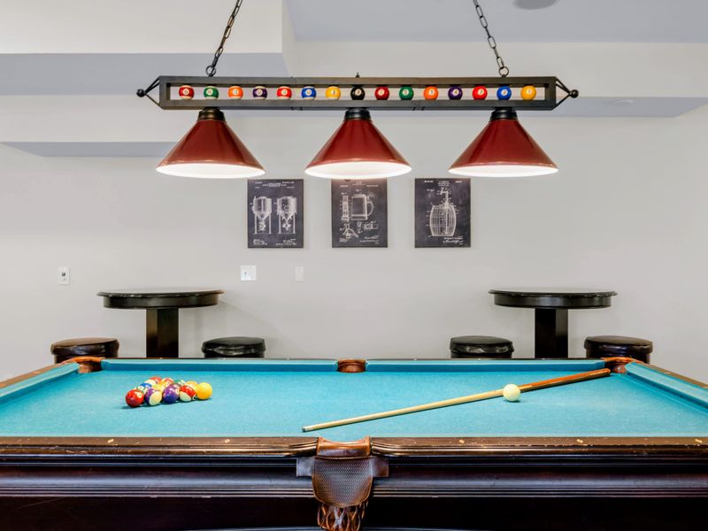 Game Room - Racked and ready, the pool table glows under a billiard-themed light with pub seating for the gallery.