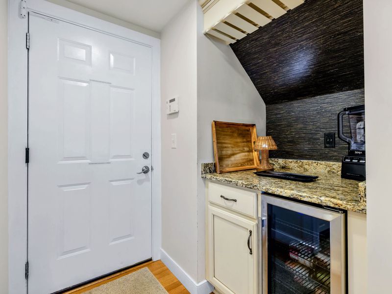 Kitchen - A tucked away drink station with granite counter, glass front beverage fridge, stemless wine glasses in the cabinet, and a blender ready for frozen drinks.