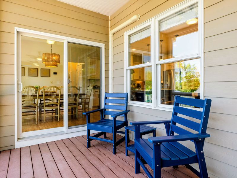 Deck and Porches - A pair of navy chairs sits just outside the kitchen sliders, a quiet screened-in spot for morning coffee.