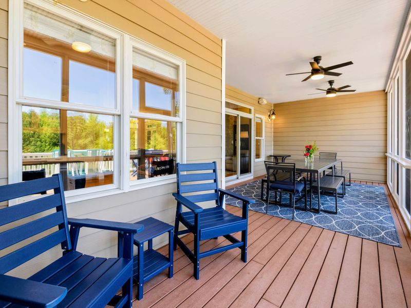 Deck and Porches - The long screened porch stretches past lounge seating to the group dining table at the far end.