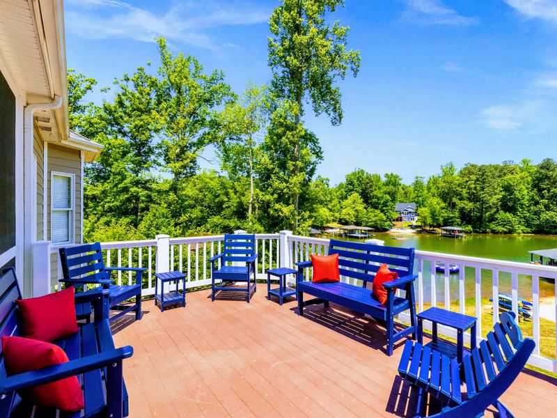 Deck and Porches - Navy benches and bright red pillows line the open upper level, the cove sparkling just past the railing.