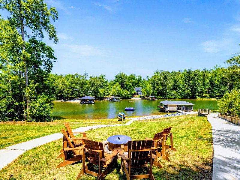 Lakefront - A circle of Adirondack chairs sits high on the lawn, overlooking the beach, boathouse, and water trampoline below.