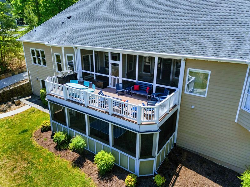 Lakefront - The open deck stacks above a screened lower porch, grill and lounge seating laid out for the evening crowd.