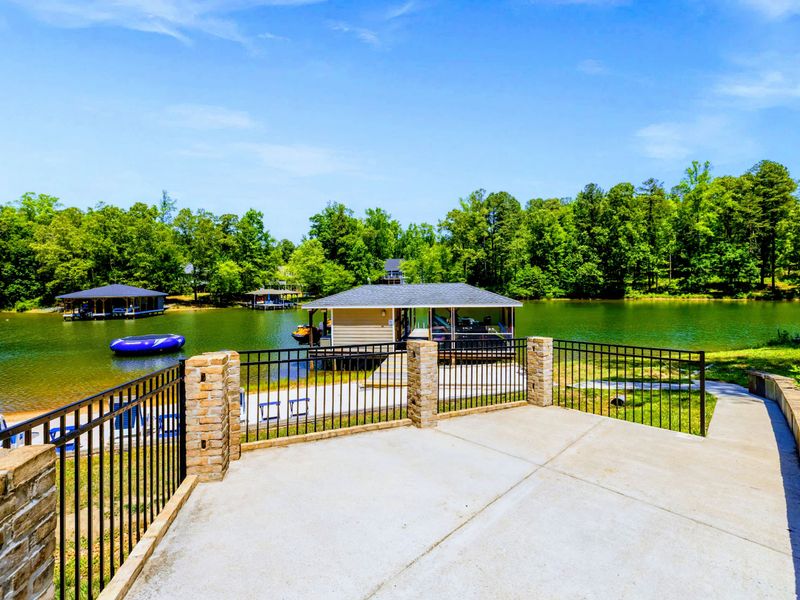 Lakefront - From the stone-and-iron overlook, take in the whole cove, boathouse below and trampoline drifting offshore.