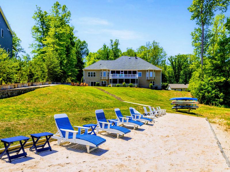 Lakefront - Loungers and side tables line the private sandy beach, kayaks and standup paddleboards racked and ready a few steps away.