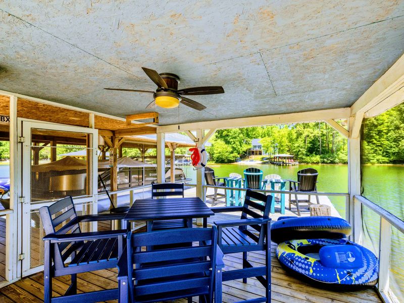 Lakefront - Shaded by the boathouse roof, a navy dining set sits under a ceiling fan with inner tubes and noodles within reach.