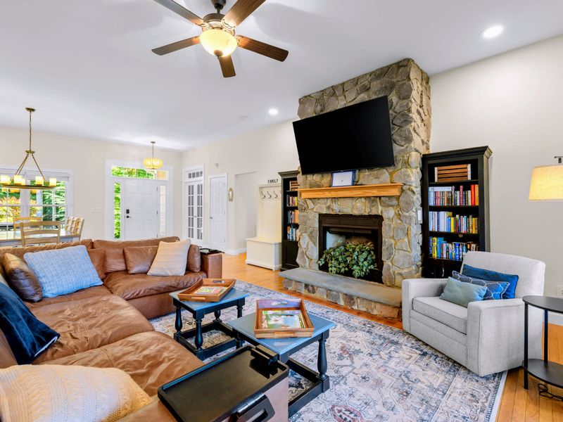 Great Room - A floor-to-ceiling stone fireplace takes center stage, flanked by book-filled shelves, a cozy reading chair and lamp, and a TV above the mantel.
