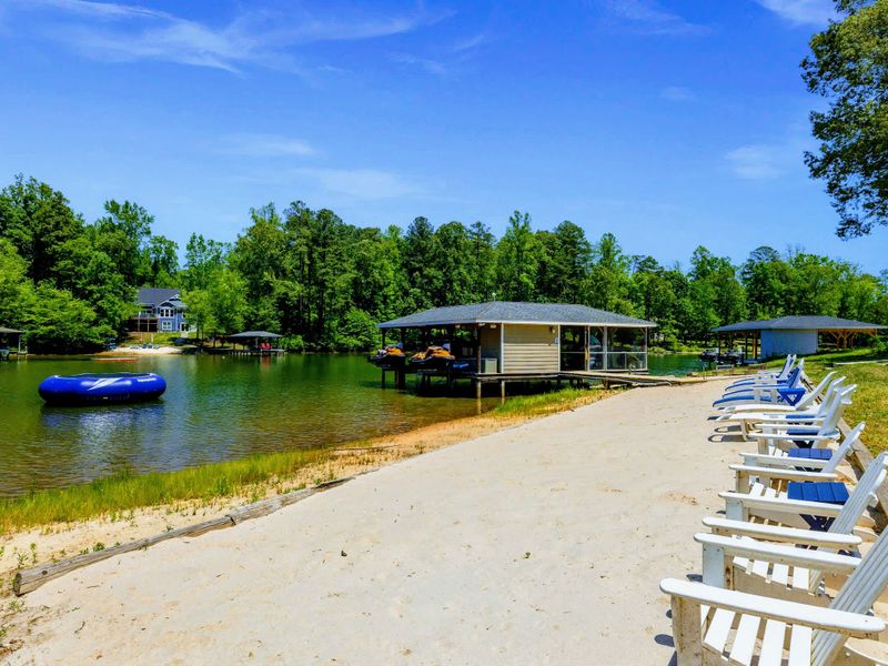 Lakefront - White Adirondack chairs face the water along the sandy beach, the trampoline and covered dock a short stroll down.