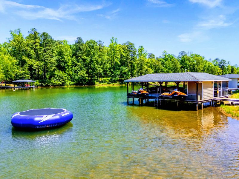 Lakefront - The water trampoline floats front and center in the quiet cove, with the covered boathouse standing just beyond.