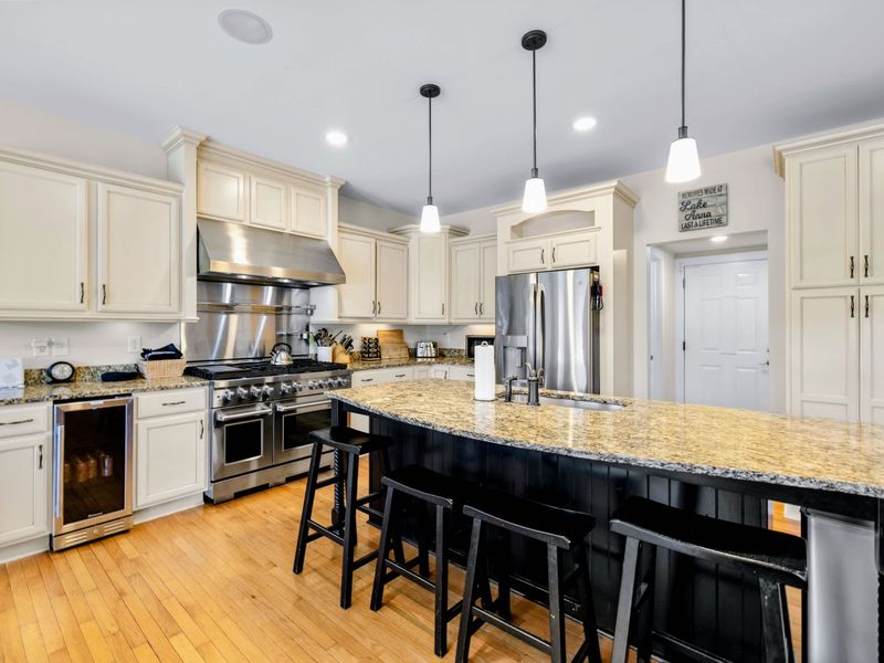 Kitchen - Granite island seating sits across from the stainless range and fridge, with a glass-front beverage cooler ready for lake days.