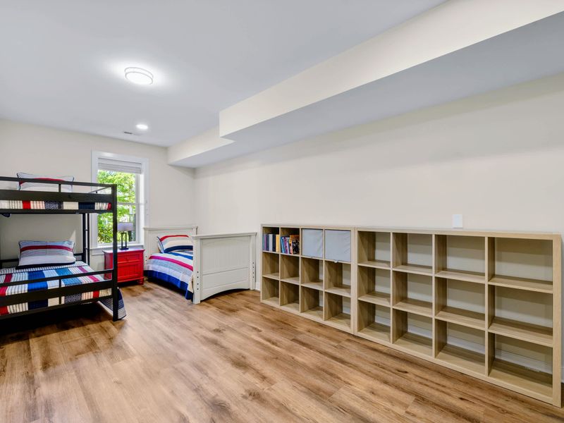 Lower Level Bunk Suite - Cubby shelving runs the length of one wall, opposite the metal bunk and a twin by the window.
