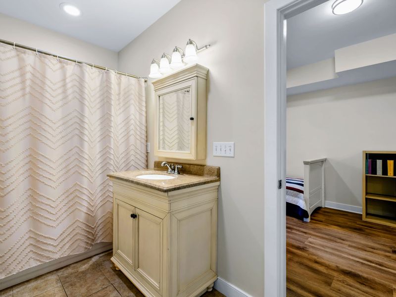 Lower Level Bunk Suite - The ensuite bath sits right off the bunk room, with a single vanity and lighted mirror cabinet.