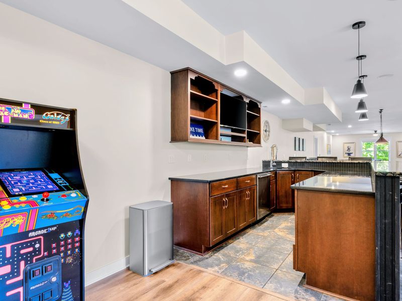 Game Room - The Ms. Pac-Man and Galaga cabinet stands ready beside the bar, a little vintage arcade between rounds.