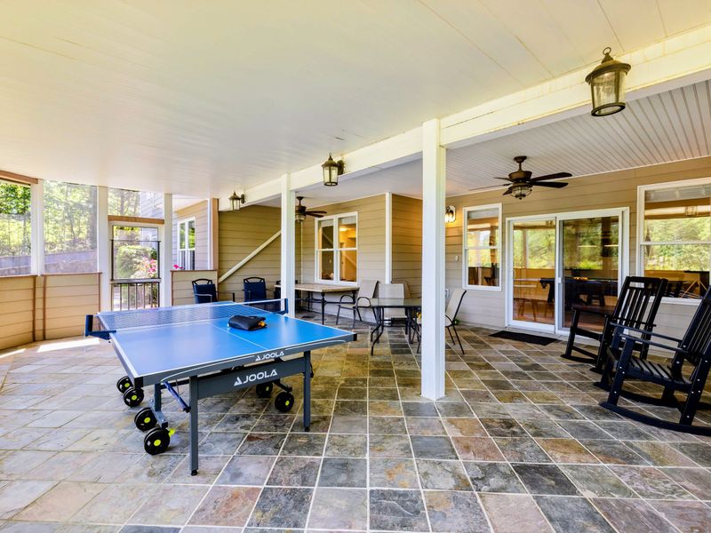 Patio - Tiled screened porch where rocking chairs and dining seating share space with the ping pong table.