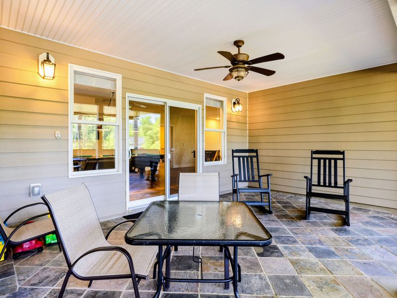 Patio - A shaded corner with a glass-top table and rocking chairs, steps from the sliding doors inside.