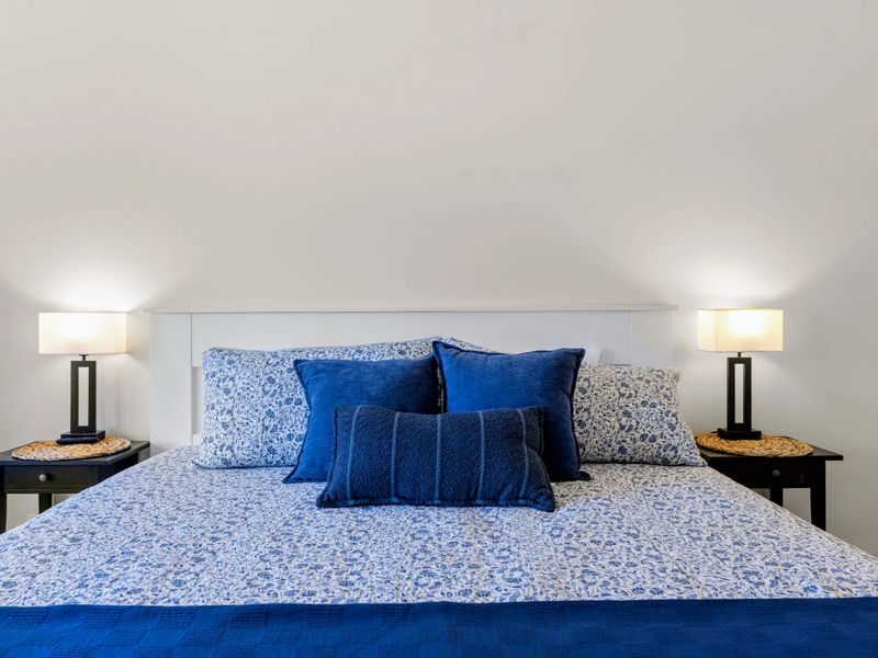 Secondary Suite - Crisp blue and white linens layer the king bed, matching lamps glowing on either side.