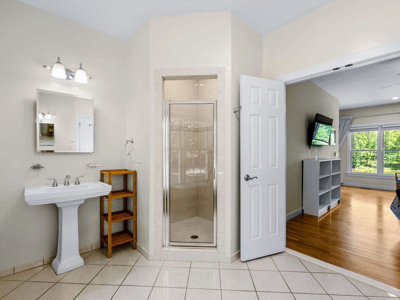 Secondary Suite - One of two pedestal sinks in the ensuite bath, with a glass-door shower.