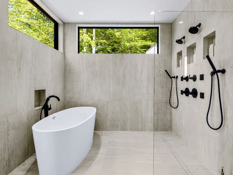 Primary Bath - Freestanding tub and glass shower, finished in stone and matte black.
