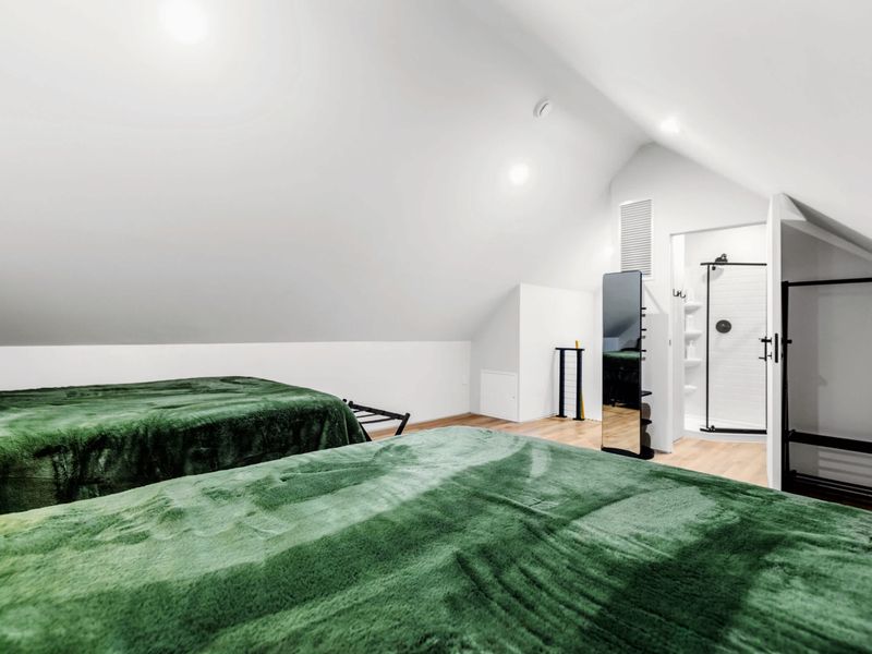 Library Suite - Two queen beds in deep green under the vaulted ceiling, sleeps four.