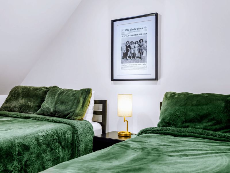 Library Suite - A green queen bed and framed art in the bright upstairs room.