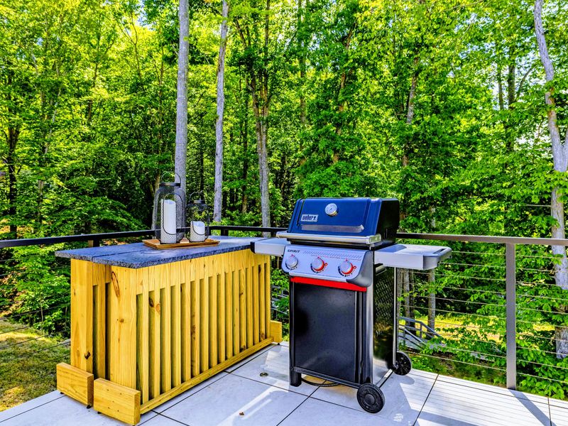 Grill Station - A gas grill and cedar prep counter on the deck, set against the trees and ready for a cookout.