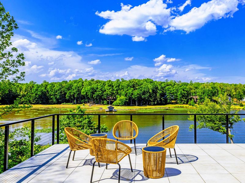 Sunset Patio - Woven chairs gathered at the deck's edge, the cove and far shoreline filling the view.