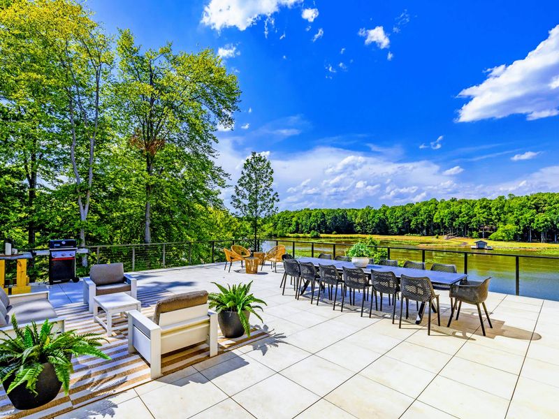 Sunset Patio - The full open deck in one frame: lounge seating, a long dining table, the grill, and the lake beyond.