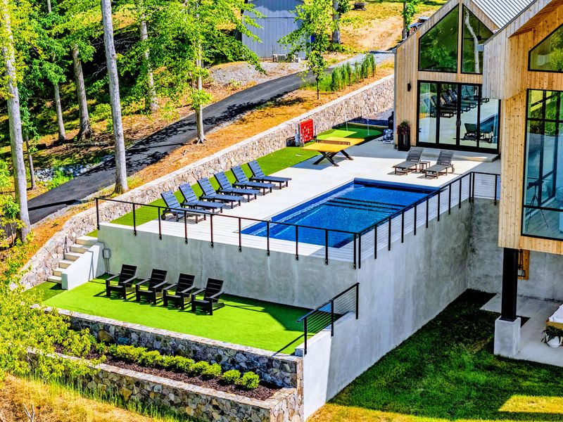 Aerial View - The pool deck from above, blue water against green canopy.