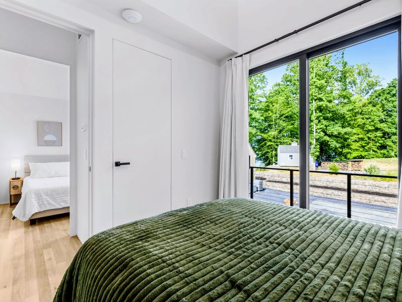 Garage Apartment Queen - A green queen bed with glass doors opening to the deck.